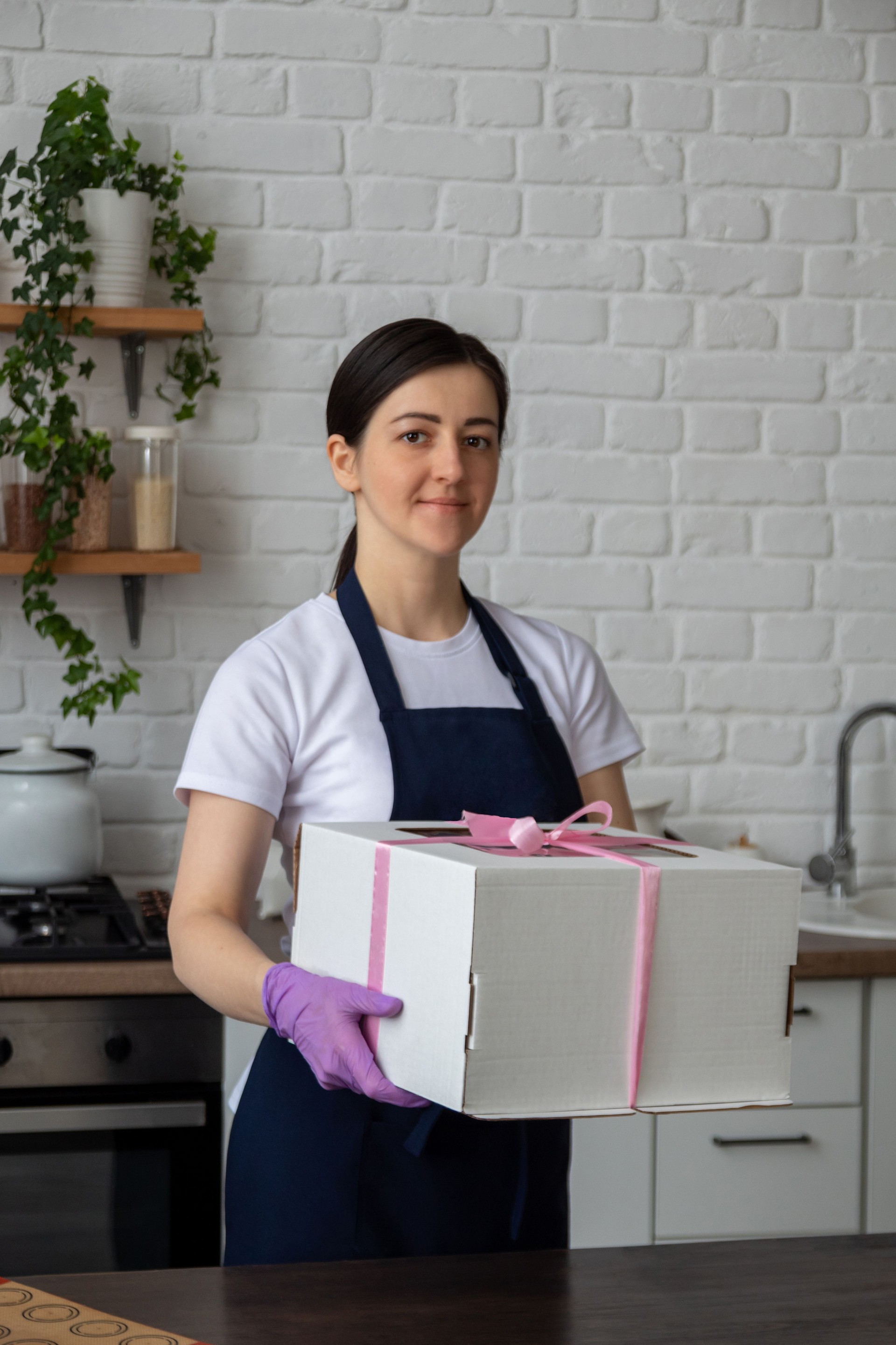Pastry chef in an apron is holding box with cake for delivery. Selective focus. Photos about confectioners, food, hobbies.